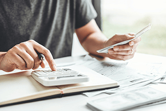 man using calculator and holding cash